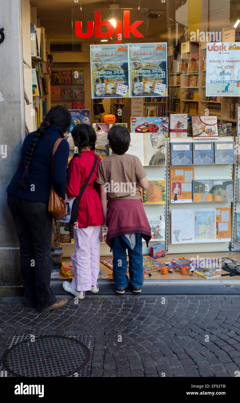 Mother and children looking in a window of a bookshop in Lucca, Tuscany, Italy Stock Photo