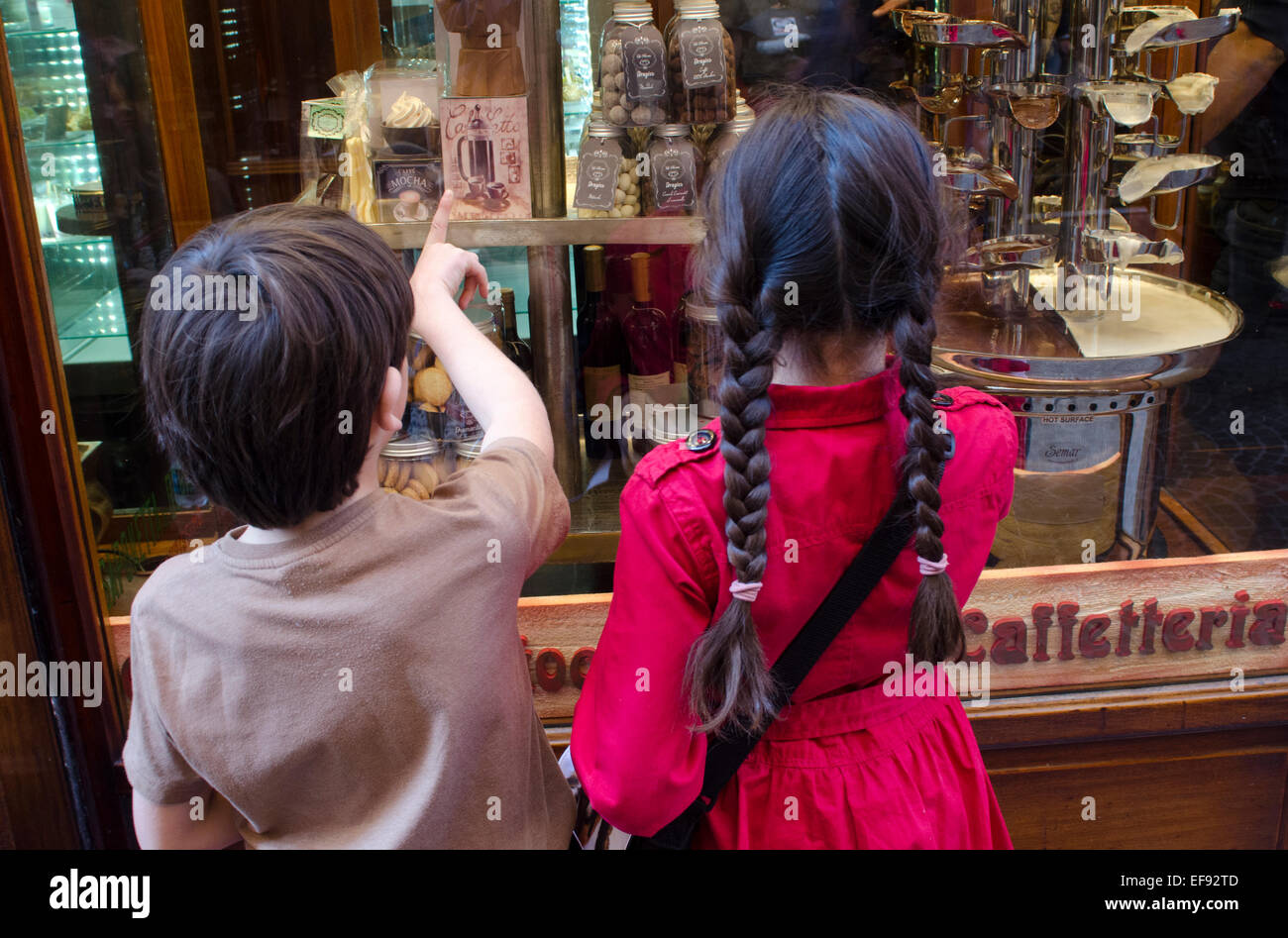 Two young children looking at confectionary in the window display of a cafe in Lucca, Tuscany, Italy Stock Photo