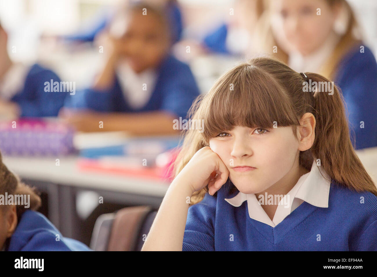 Elementary schoolgirl looking bored during lesson Stock Photo