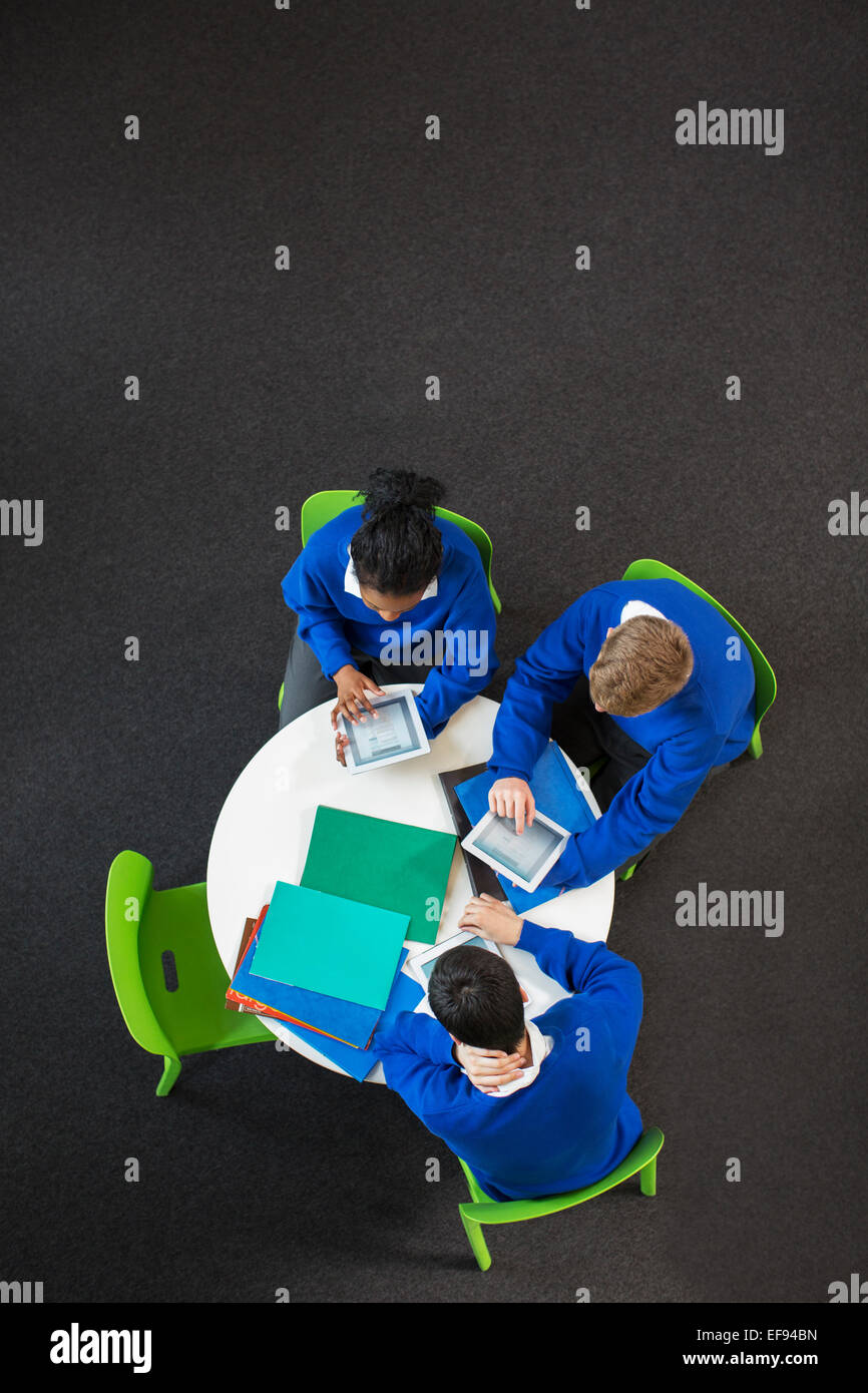 Overhead view of high school students sitting at round table with digital tablets Stock Photo