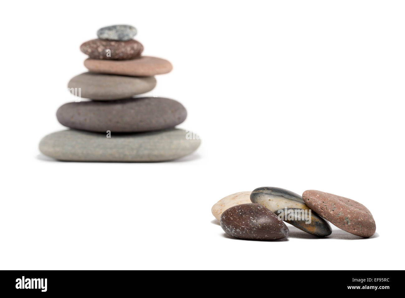 Stone cairn made from a variety of colorful rocks.  Four extra stones in foreground are in sharp focus. Cairn is in soft focus. Stock Photo