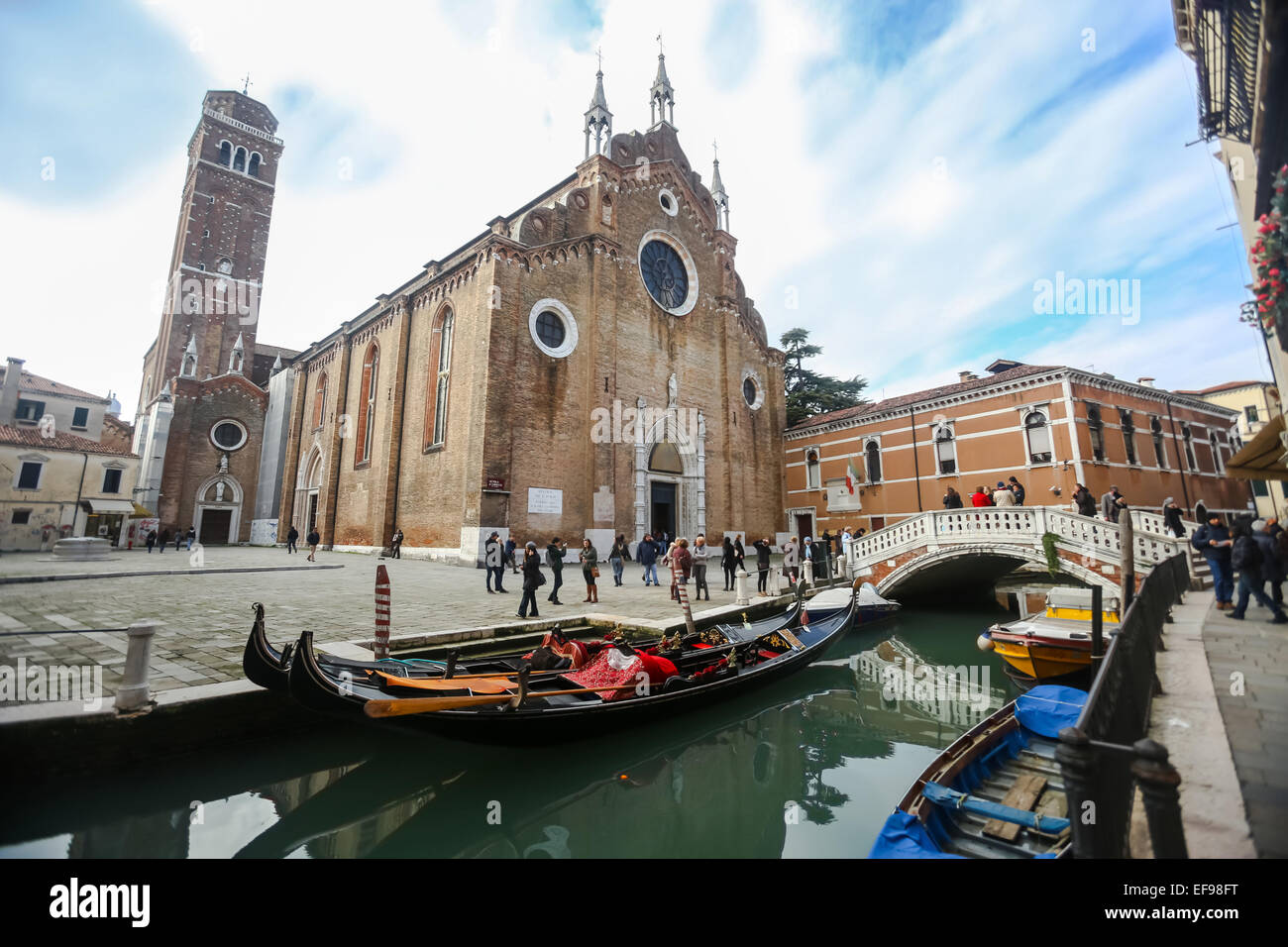 A view of gondolas moored in the water canal in front of the Basilica di Santa Maria Gloriosa dei Frari in Venice, Italy. Stock Photo