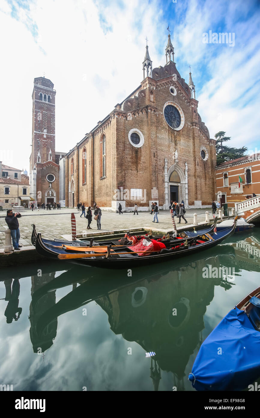 A view of gondolas moored in the water canal in front of the Basilica di Santa Maria Gloriosa dei Frari in Venice, Italy. Stock Photo