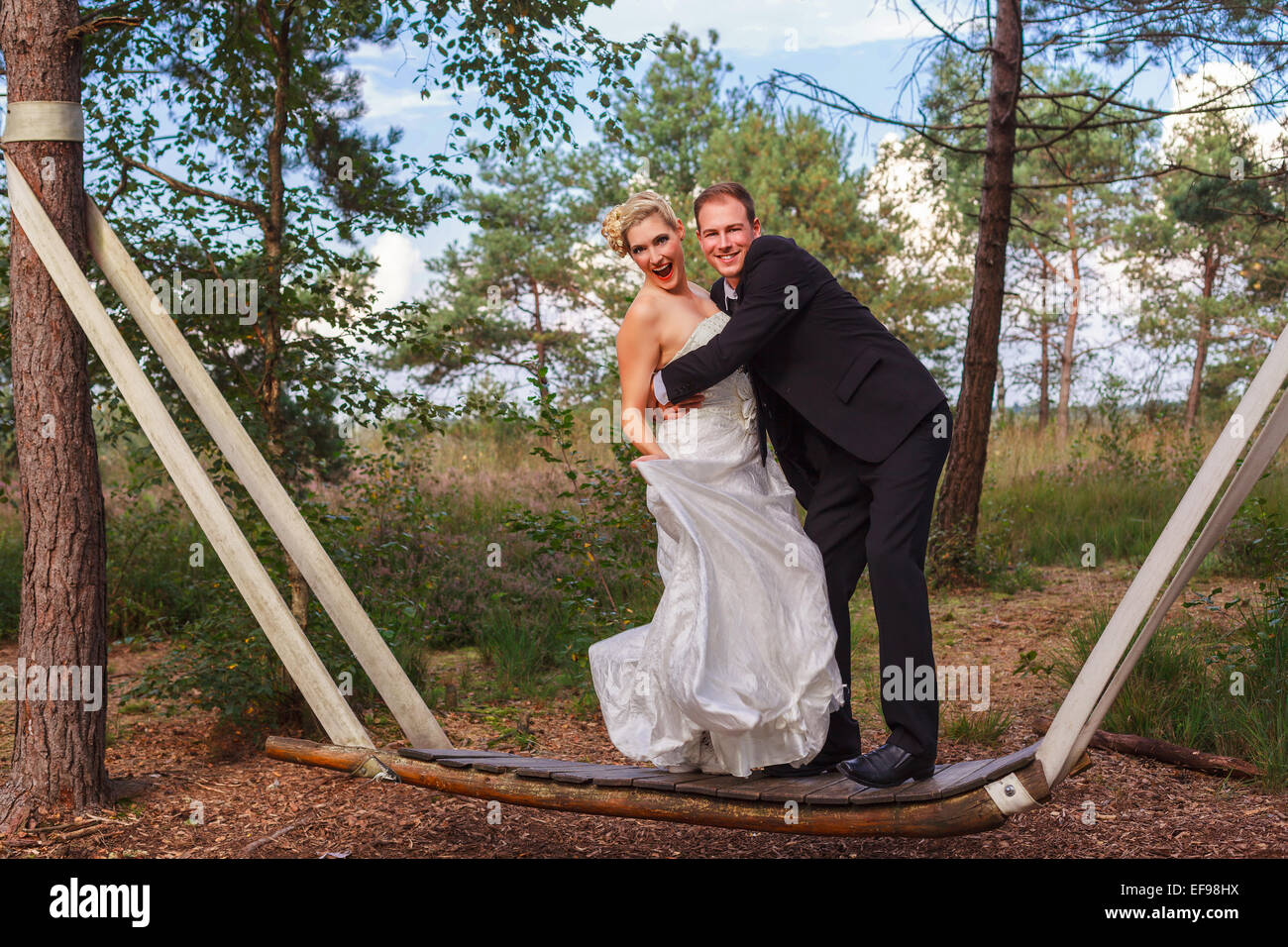 Bride and groom standing on a swing in the forest Stock Photo - Alamy