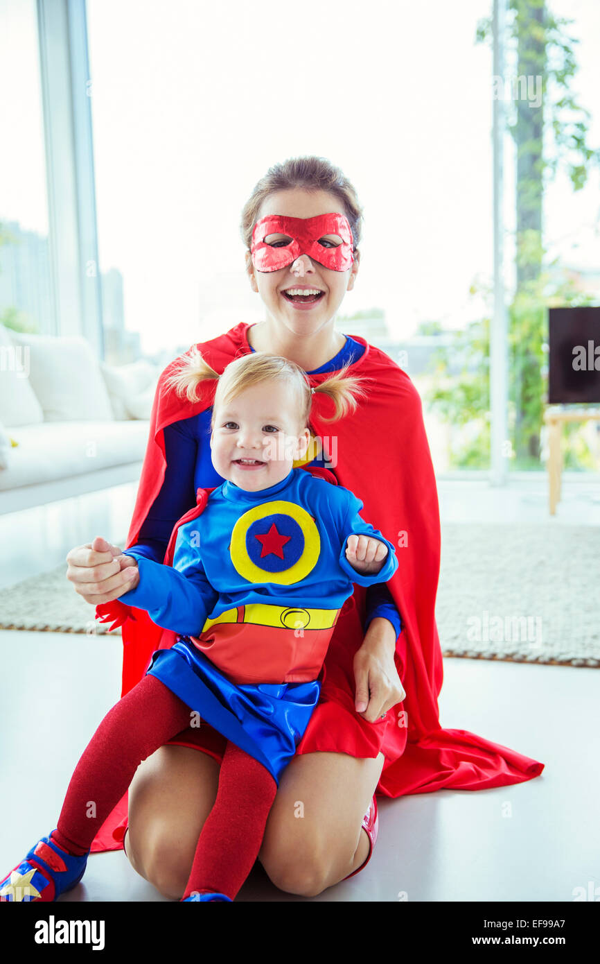 Superhero hugging daughter on living room floor Stock Photo