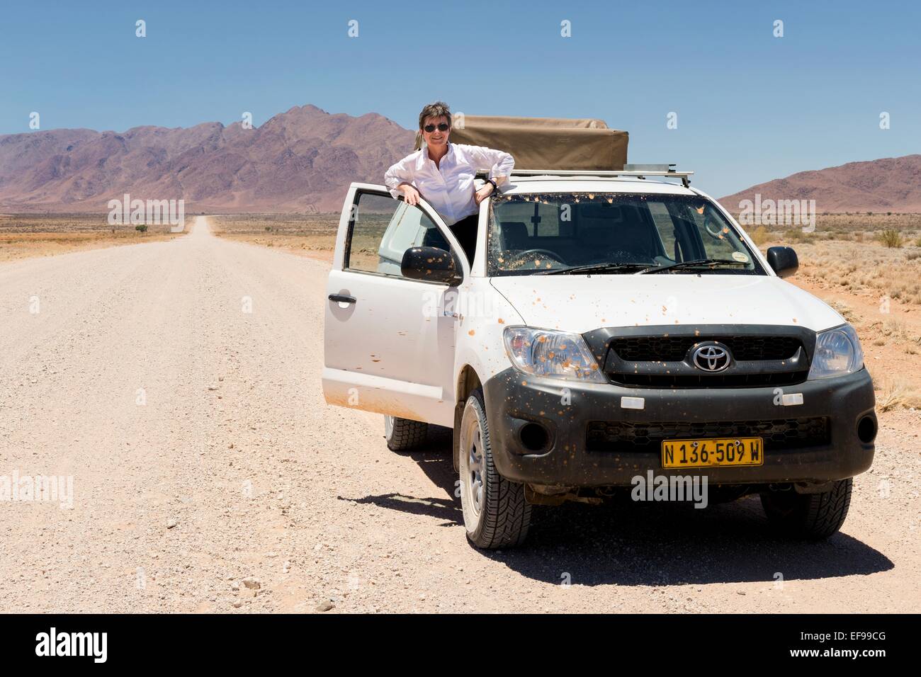 A woman stops for a picture while driving north on the C4 route from Sesriem to Swakopmund, Namibia, Africa. Stock Photo