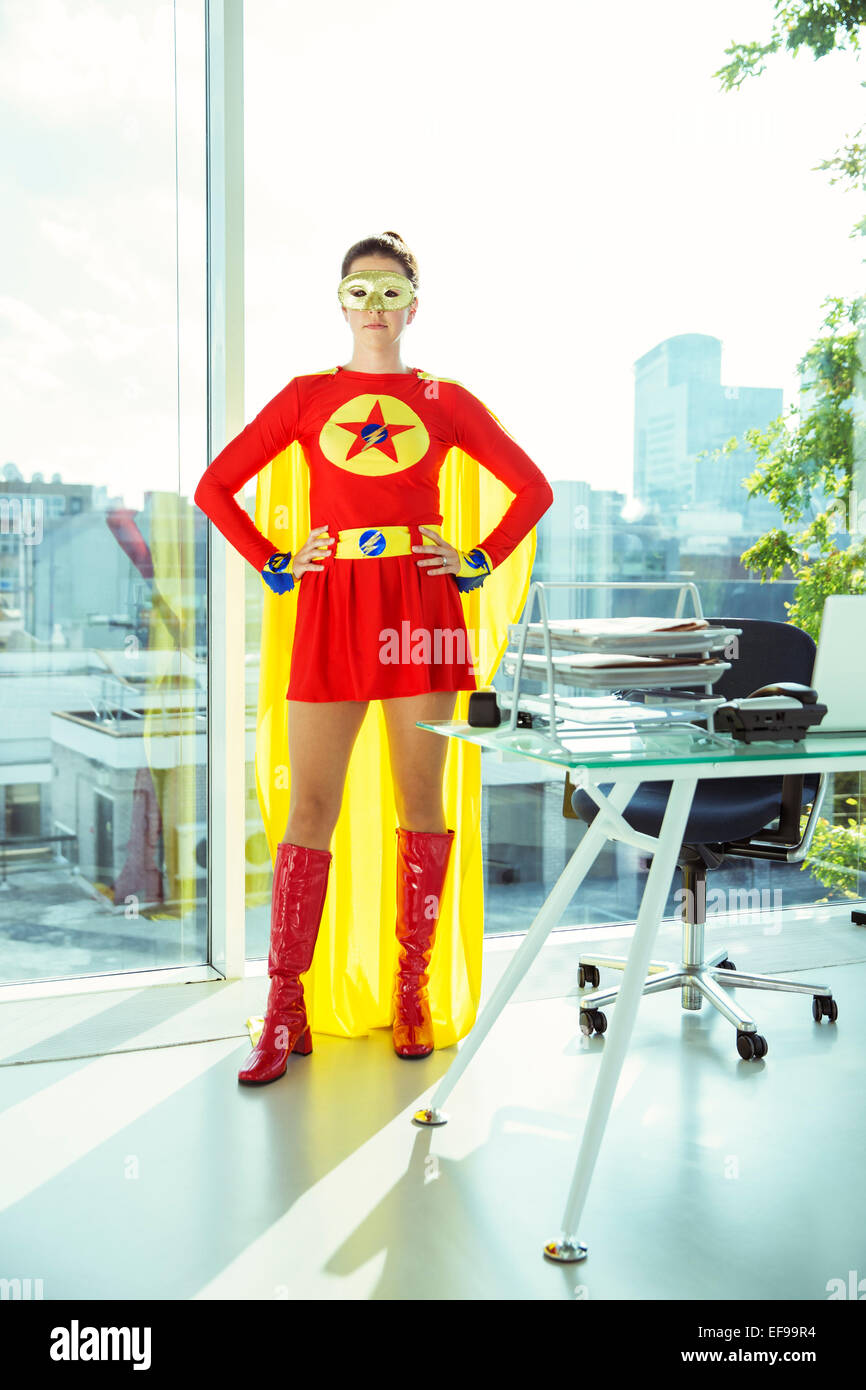 Superhero standing with hands on hips in office Stock Photo