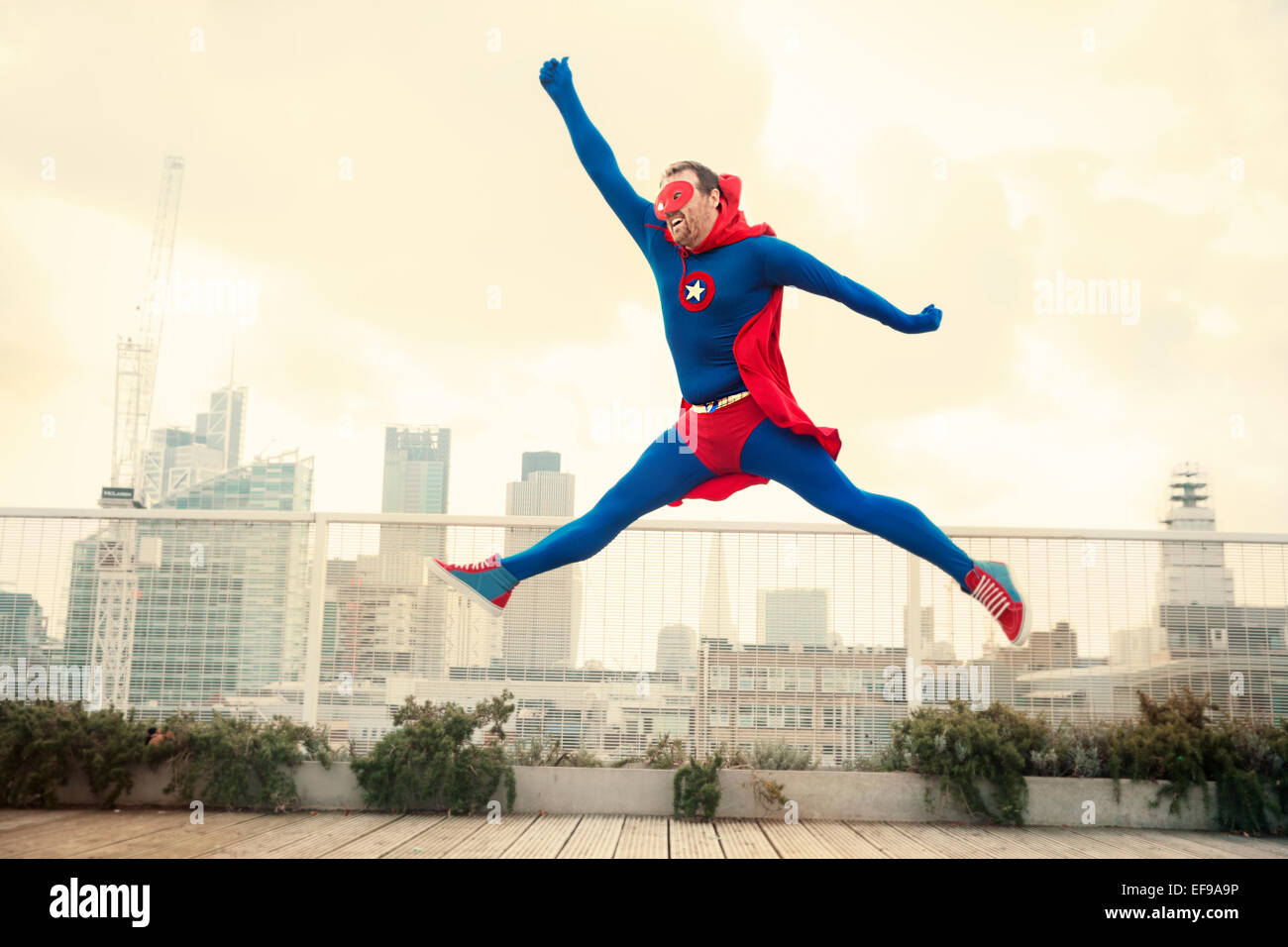 Superhero jumping on city rooftop Stock Photo Alamy
