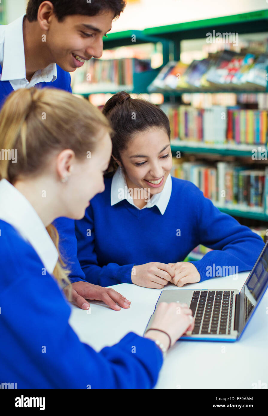 Students working with laptop in library and smiling Stock Photo