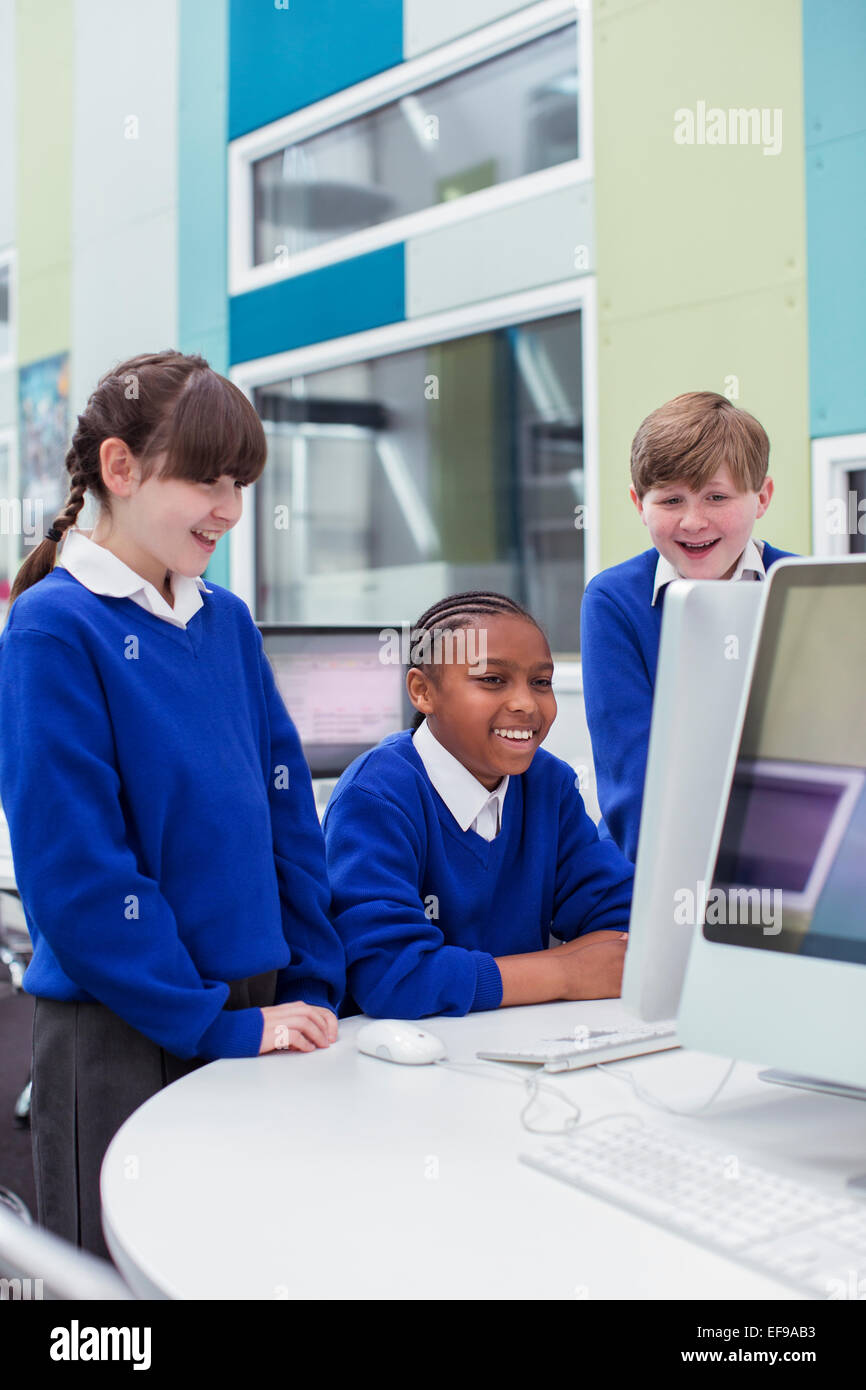 Primary school children looking at computer and smiling Stock Photo