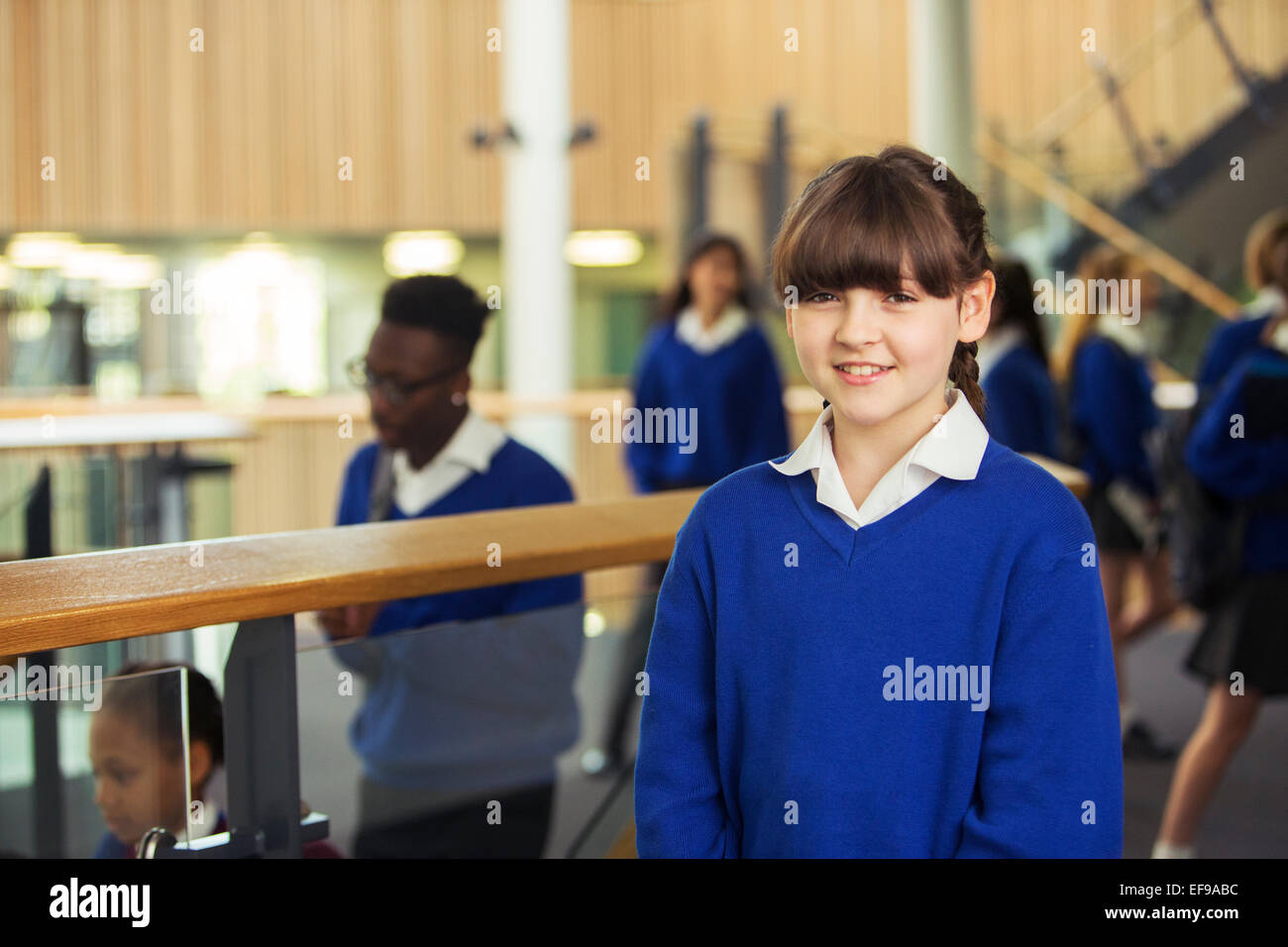 Portrait of smiling elementary school girl wearing blue school uniform standing in school corridor Stock Photo