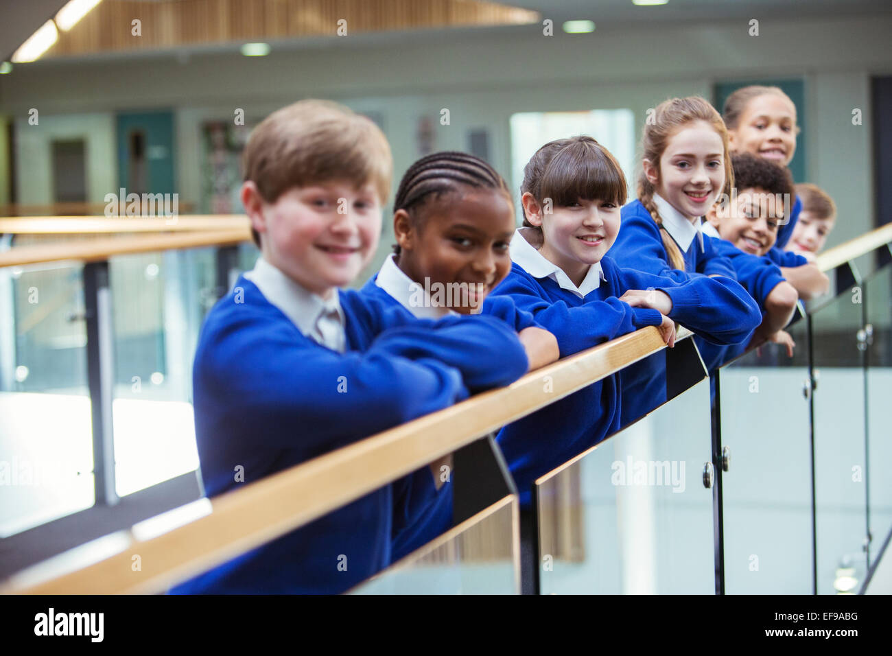Portrait of elementary school children wearing blue school uniforms standing in school corridor Stock Photo