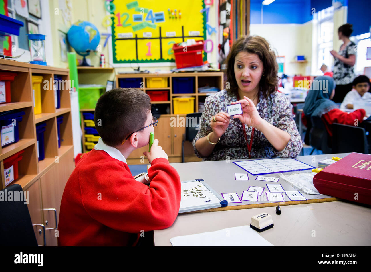 Learning support assistant (LSA) with Special educational needs and Disability (SEND) child in classroom Stock Photo
