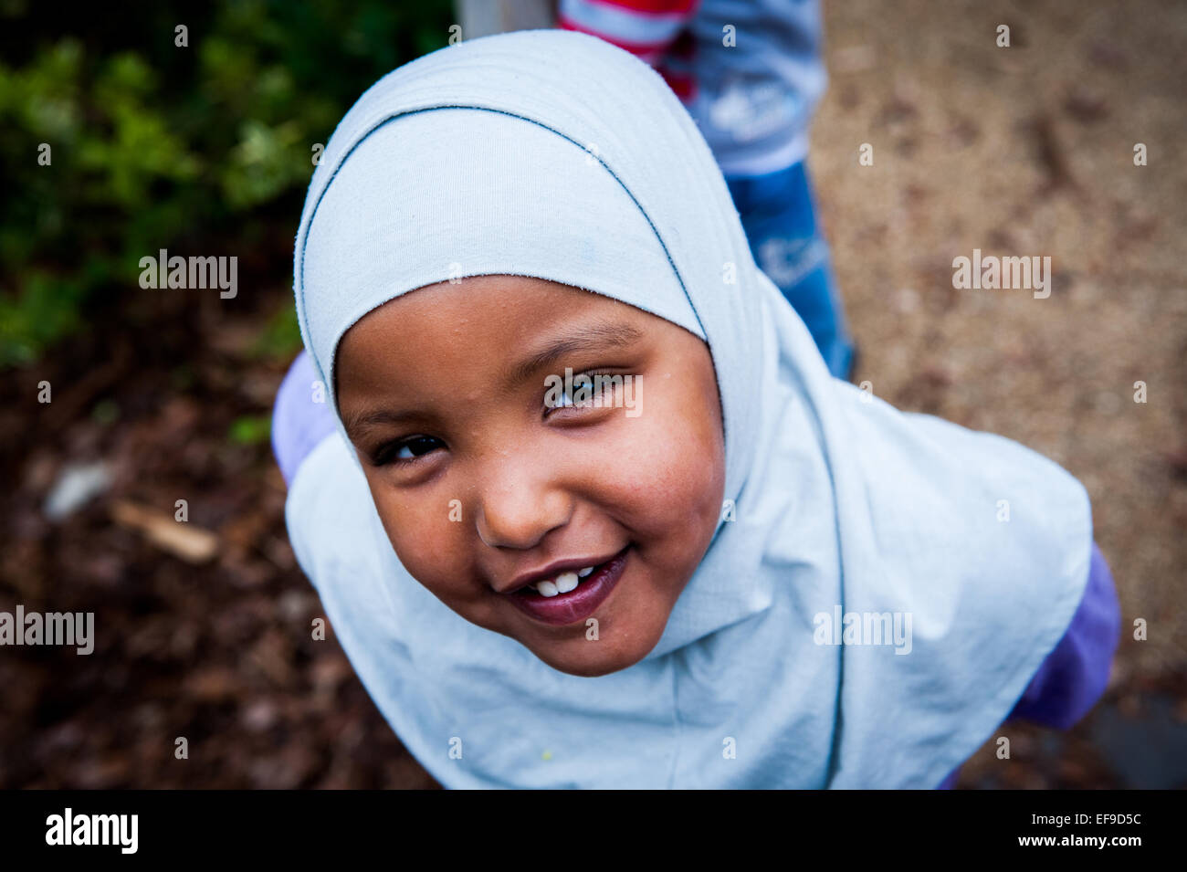 Happy Smiling muslim girl in headscarf in the playground of  Primary school in London W2 Stock Photo