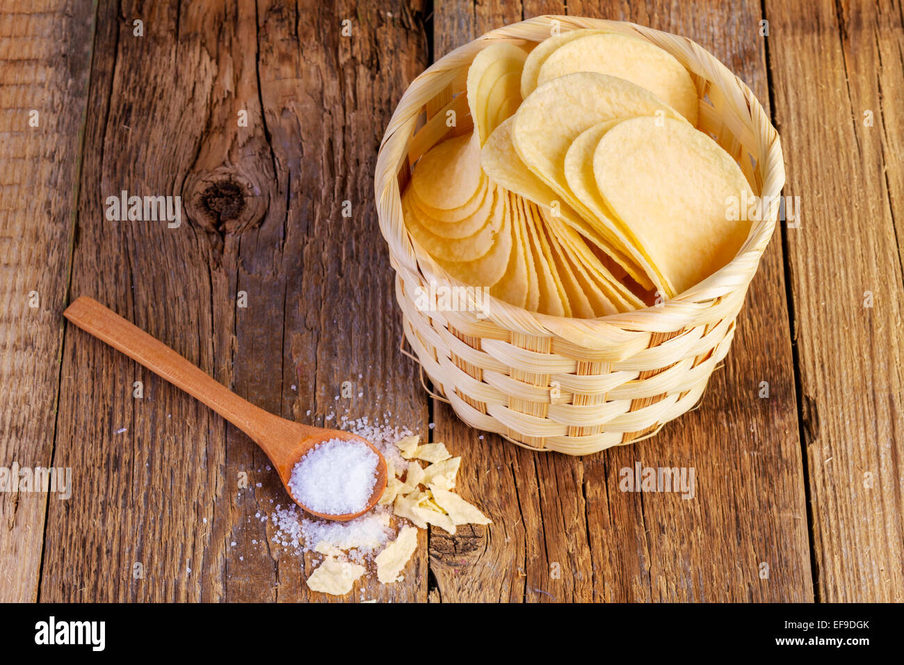 potato chips in a wooden basket and spoon on wooden table Stock Photo