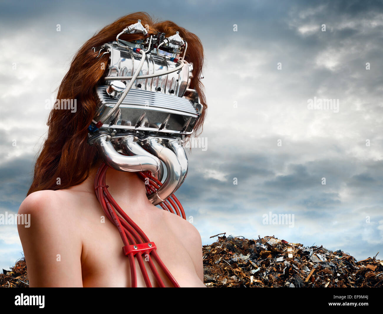 Horizontal fantasy image of woman with a car engine for a head with a junkyard behind her Stock Photo