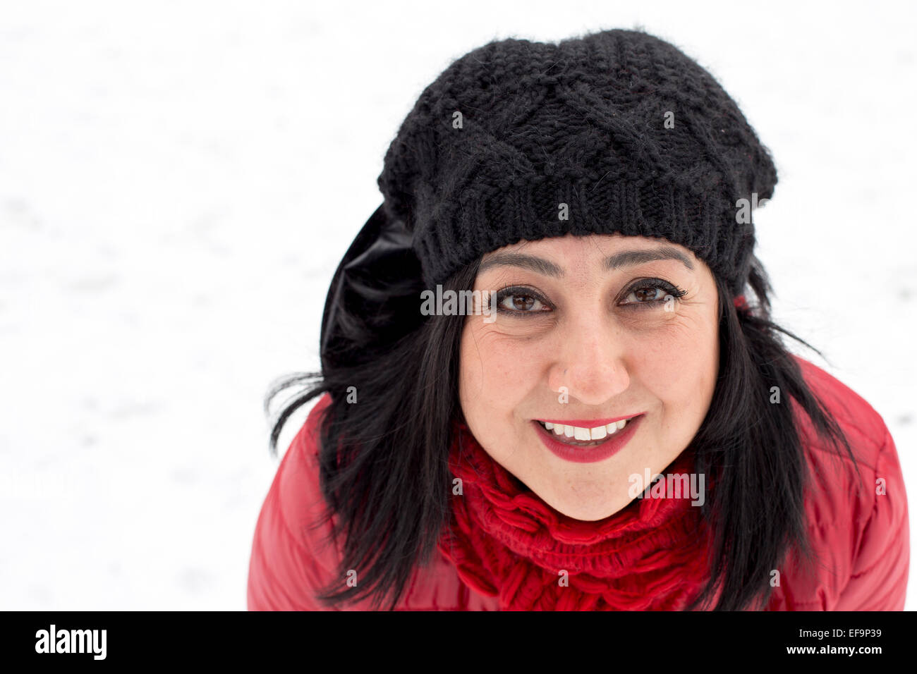Black haired Turkish women looking at the camera on a snowy day background Stock Photo