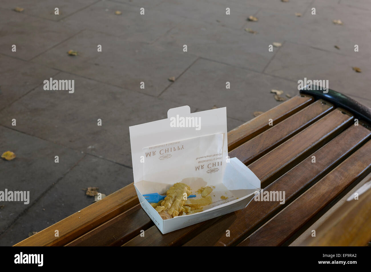 Discarded fish and chips on a city centre bench at night. York, UK. Horizontal format with copyspace. Stock Photo