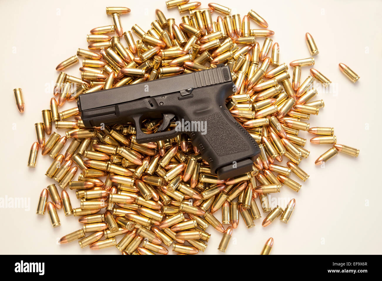 9mm Glock 19 handgun resting on pile of live ammunition on white background Stock Photo