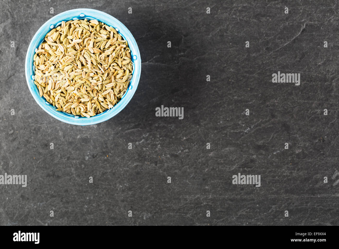 Bowl of fennel seeds on stone surface with copy space. Stock Photo