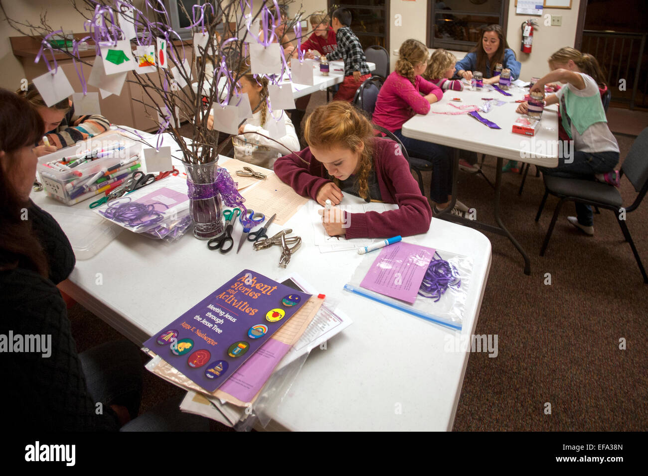 Children at St. Timothy's Catholic Church, Laguna Niguel, CA, make a Jesse tree which symbolizes the time of preparation for the celebration of the Nativity of Jesus at Christmas. Note art supplies on table and instruction book. Stock Photo