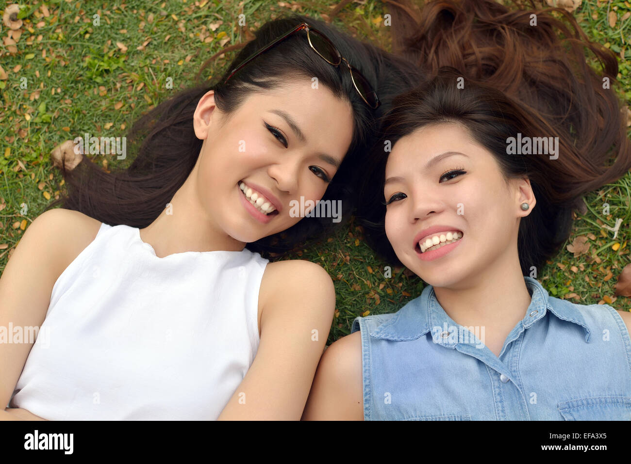 Portrait of Two Beautiful , Young Women , Lie Down on Lawn Stock Photo