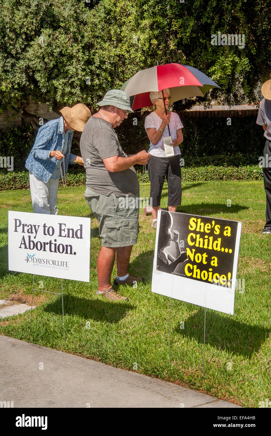 Holding a rosary, a Catholic man opposed to abortion attends a prolife vigil on a street corner in Mission Viejo, CA. Note signs. Stock Photo