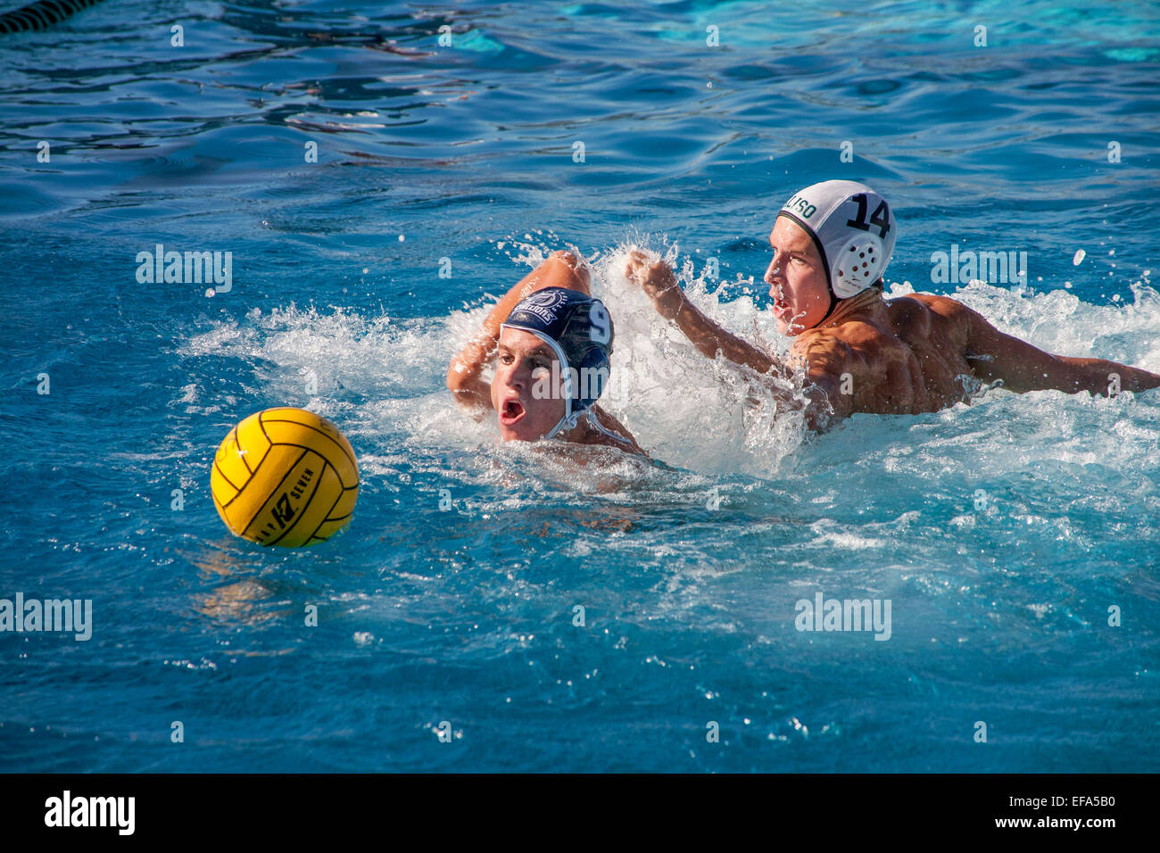 High school water polo teams compete in San Juan Capistrano, CA. Note numbered caps. Stock Photo