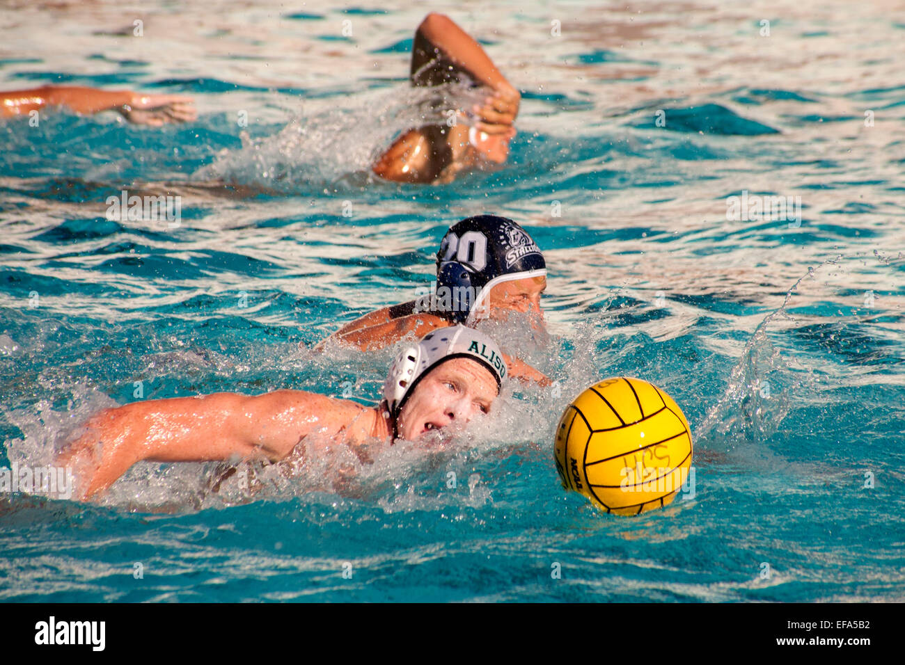 High school water polo teams compete in San Juan Capistrano, CA. Note numbered caps. Stock Photo
