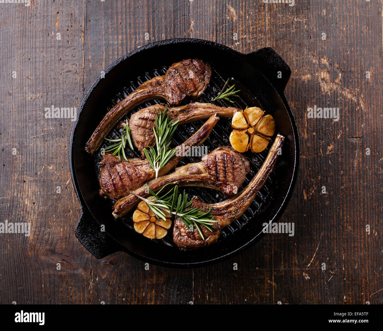 Roasted lamb ribs with rosemary and garlic on grill pan on dark