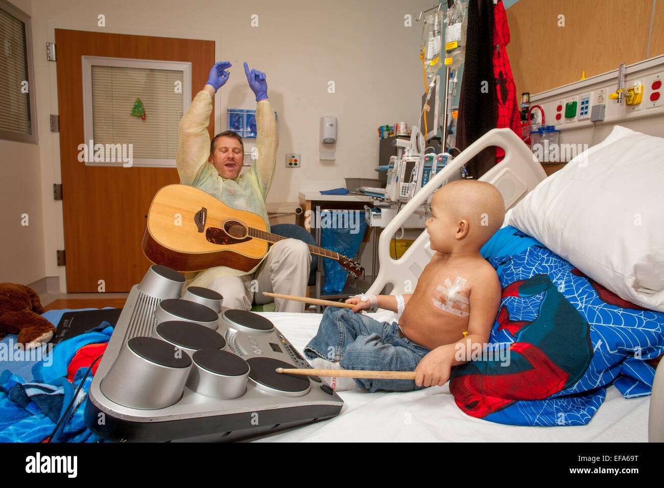Wearing a sterile gown and rubber gloves, a music therapist playing a