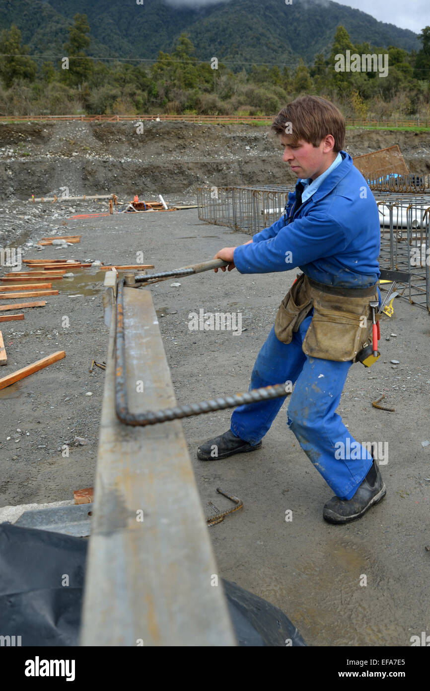 A builder bends reinforcing steel for foundations work on a large construction project Stock Photo