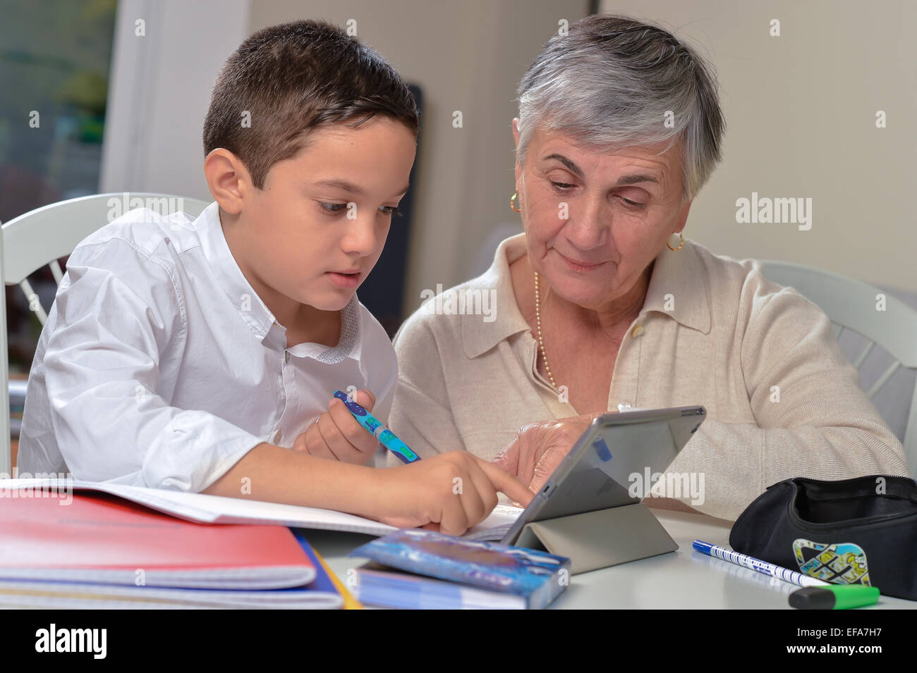 Little boy getting homework help from her grandmother at the table Stock Photo