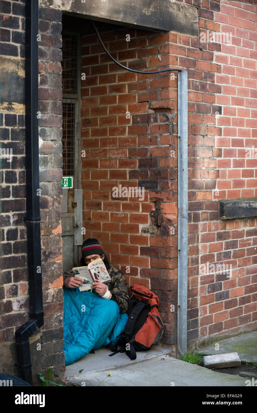 A homeless man reading a book while in his sleeping bag Stock Photo - Alamy