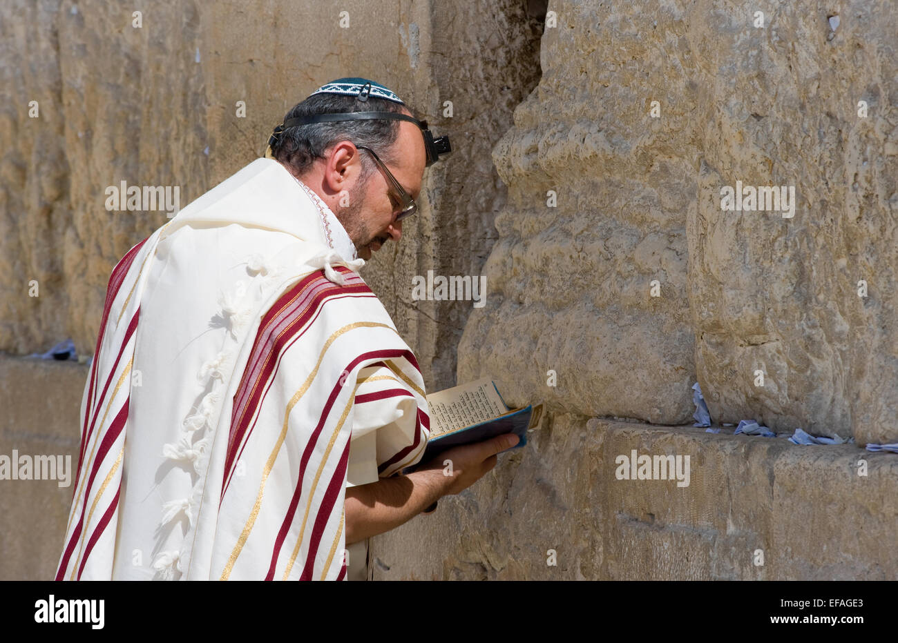 A jewish man with the torah in his hands is praying in front of the western wall in the old ci Stock Photo