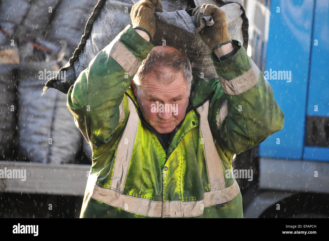 Man delivering sacks of coal in the rain. Cornwall, England, UK Stock Photo