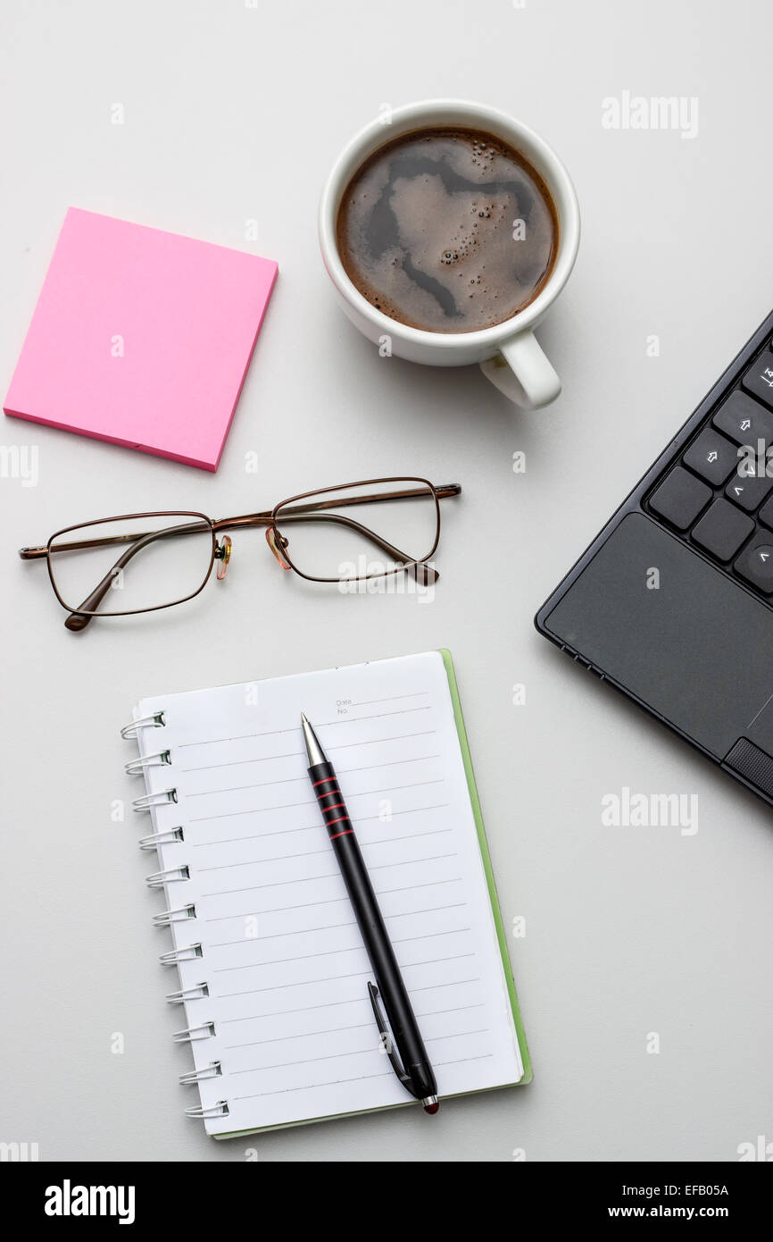Office desktop with coffee, notepad and glasses. From above Stock Photo