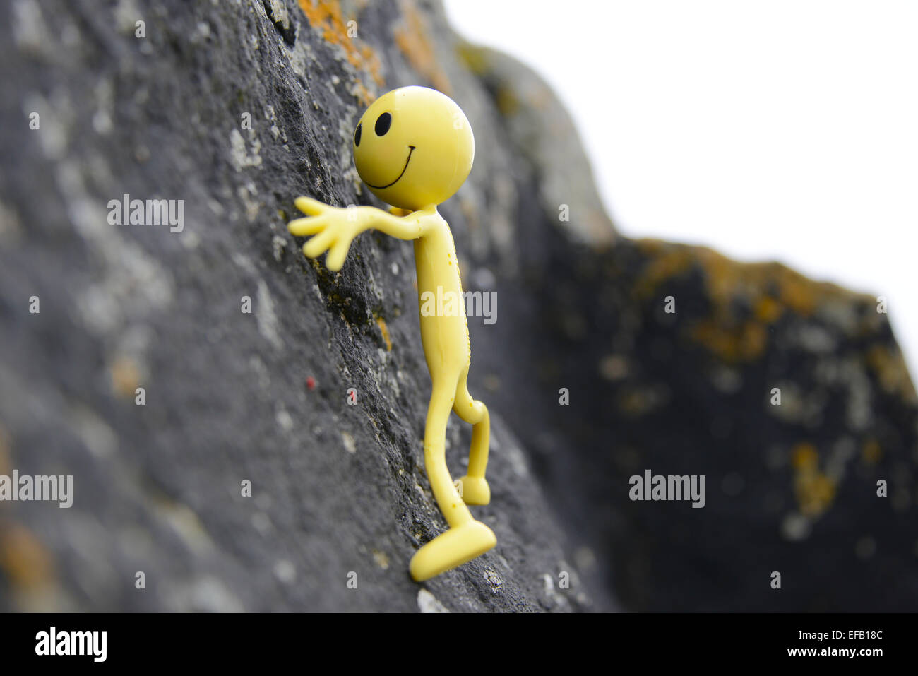 Yellow Smiley Man on holiday in the Outer Hebrides - Here he's engaging in his favourite hobby - rock climbing Stock Photo