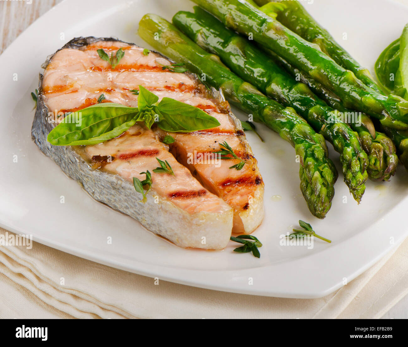Grilled salmon with asparagus  and fresh herbs on white plate. Selective focus Stock Photo
