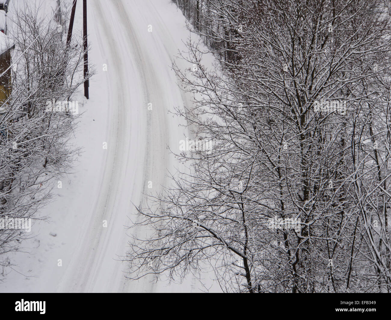 Birds eye view of a snow covered road with tire tracks and surrounding trees and houses, Oslo Norway Stock Photo