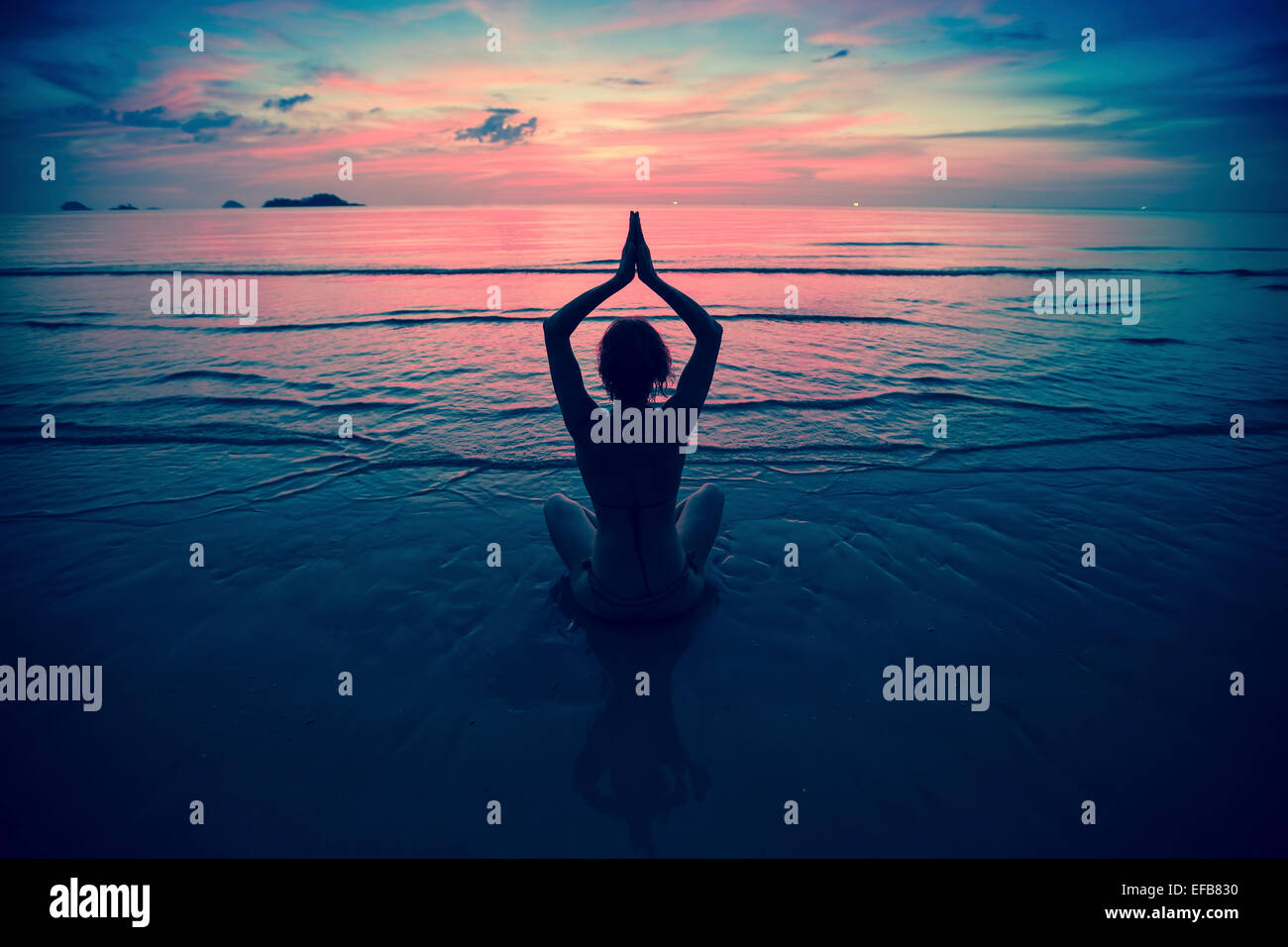 Silhouette young woman practicing yoga on the beach at surrealistic ...