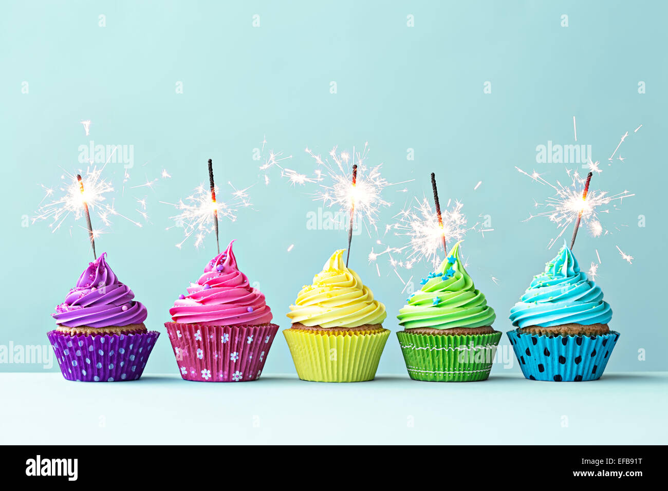 Row of colorful cupcakes with sparklers Stock Photo