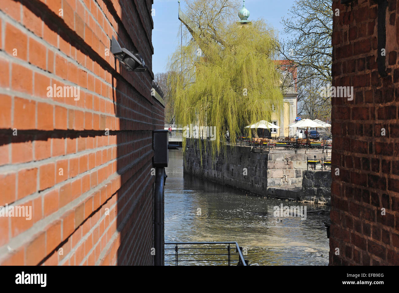 View through a gap between the walls from the historic mill buildings at the river Ilmenau and an open-air pub, 21 April 2013 Stock Photo
