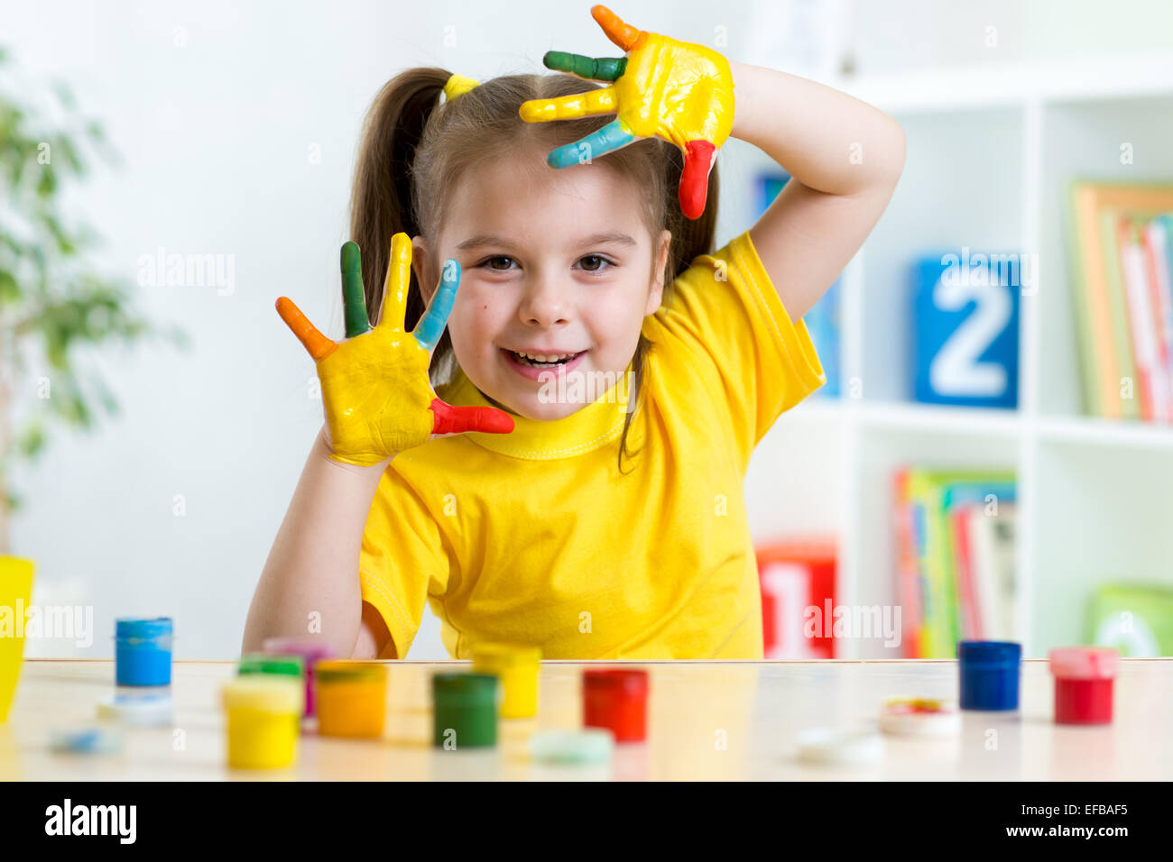 Funny little girl with hands painted in colorful paint Stock Photo
