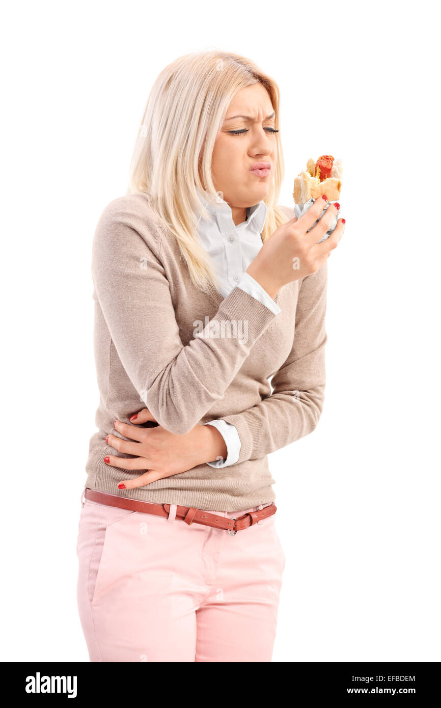 Vertical shot of a woman eating a hotdog and feeling sick isolated on white background Stock Photo