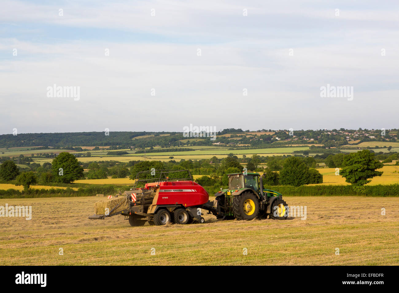 Tractor and hay baling baling hay in field, Oxfordshire, England Stock