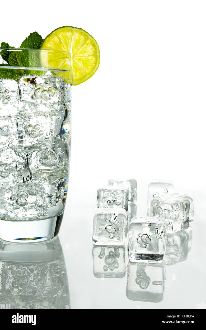 Glass of sparkling water with ice cubes garnished with a slice of lime ...
