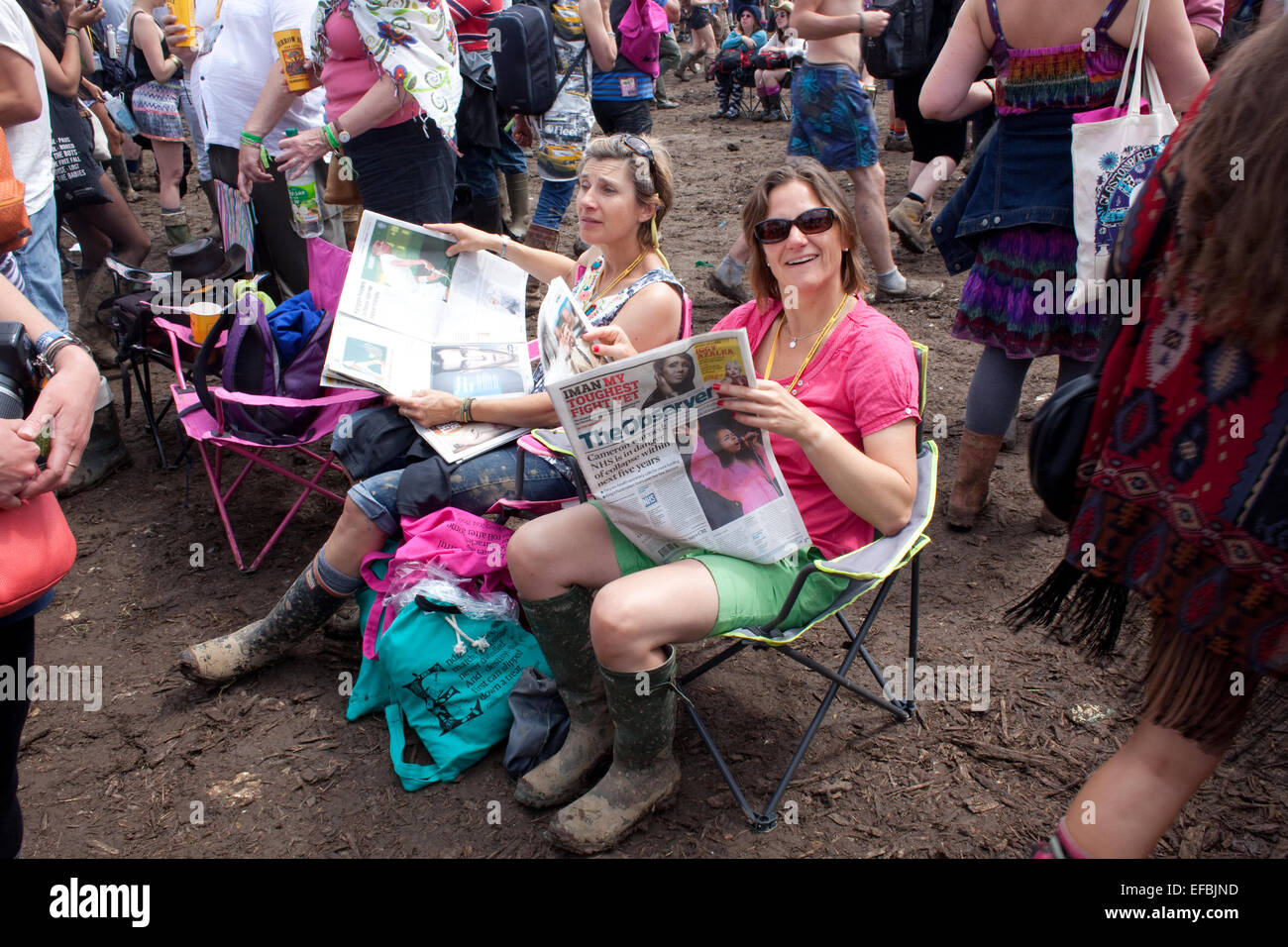 29th June 2014. Punters read newspapers near the Pyramid Stage at Glastonbury. Stock Photo