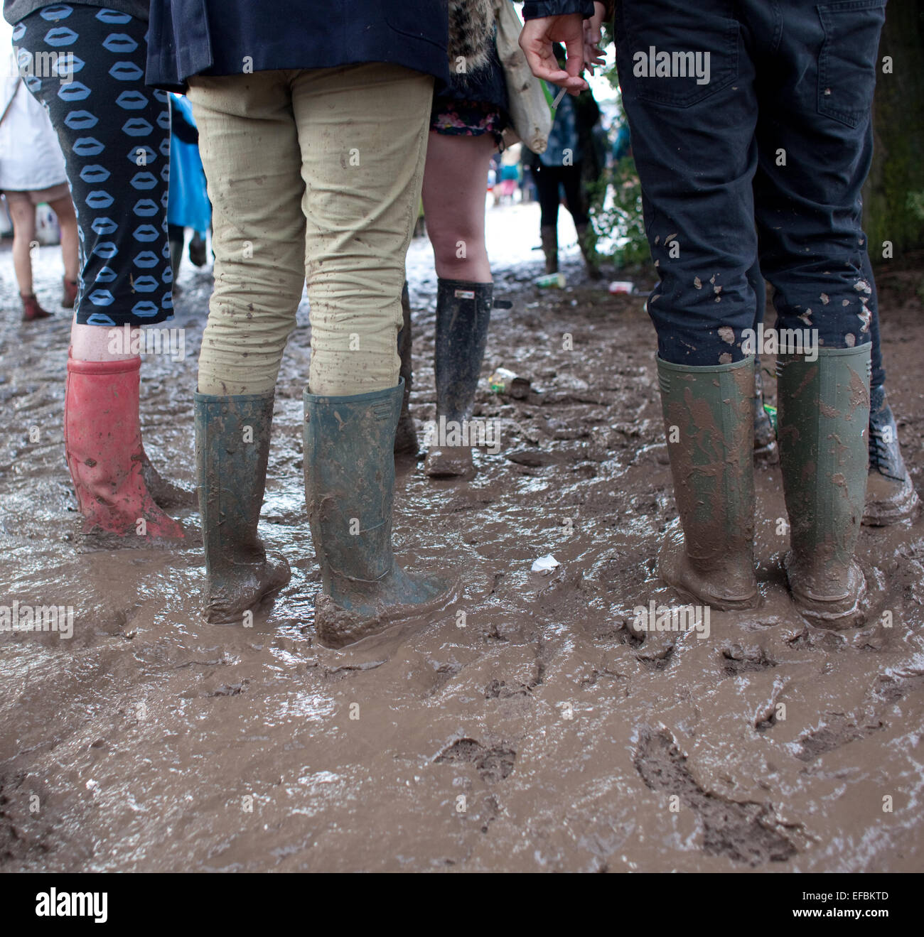 28th June 2014. People negotiate the mud on the second day of the festival. Stock Photo