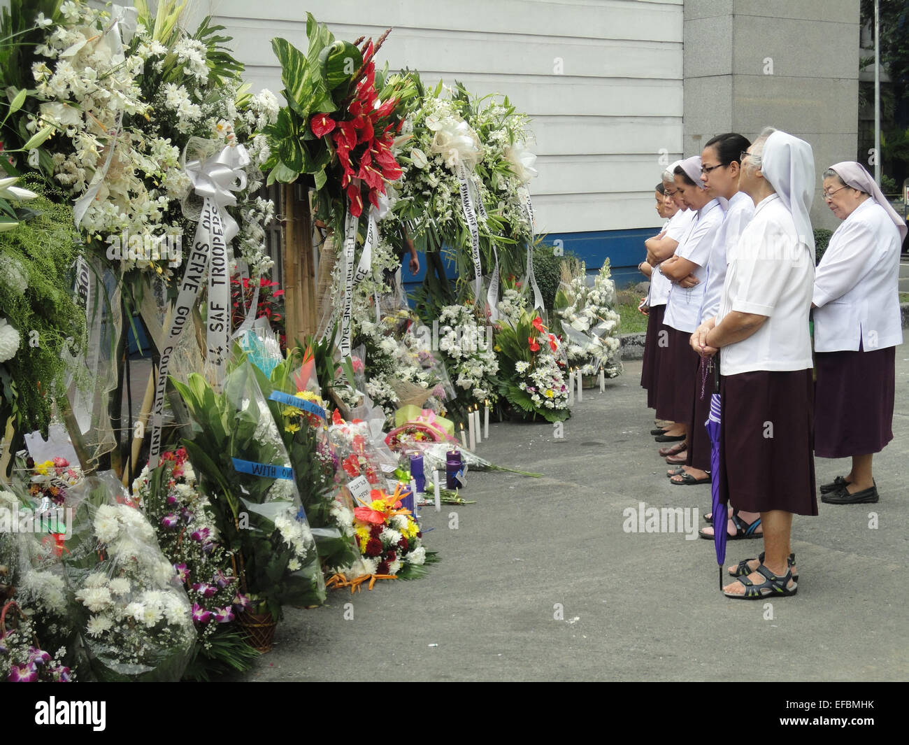 Nuns from the Religious of the Assumption pray in front of flower wreaths outside the Philippine National Police headquarters, in memory of the 44 elite commandos who were killed in an encounter against Moro seperatist rebels. Philippine President Benigno Aquino III declared a National Day of Mourning to commemorate the 44 elite commandos who were slain in an encounter at Mamasapano, Maguindanao province. © Richard James Mendoza/Pacific Press/Alamy Live News Stock Photo